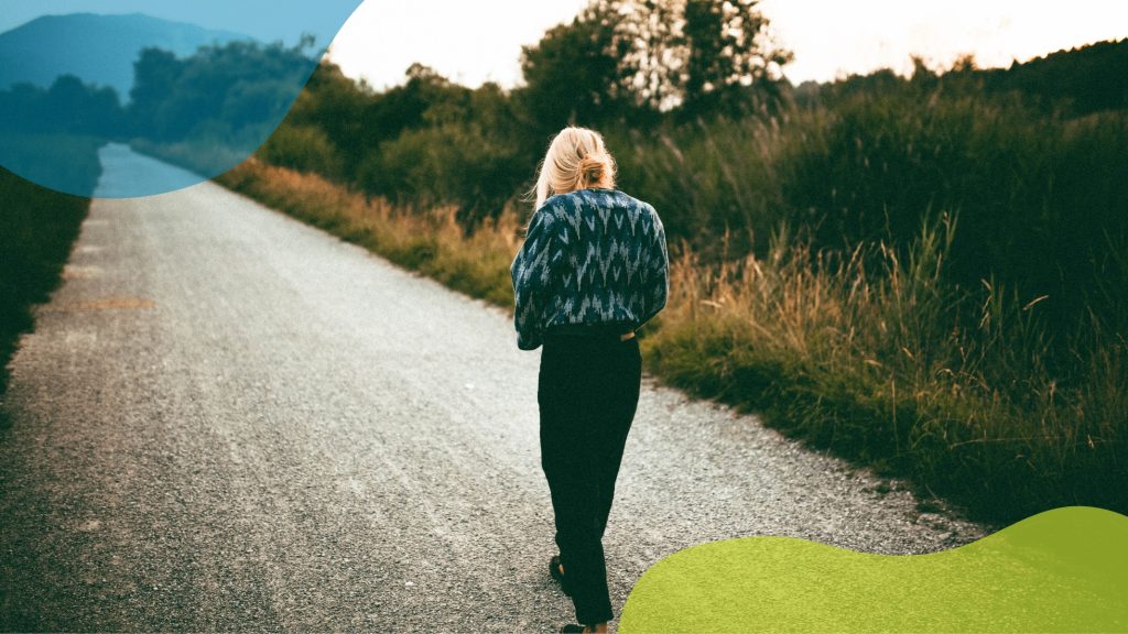 A solitary figure in a patterned jacket walks along a peaceful country path at golden hour, representing the conscious choice to find joy in quiet moments and personal journeys.
